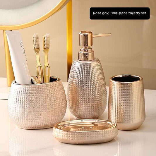 Rose gold four-piece bathroom accessory set on a marble surface with a mirror in the background.